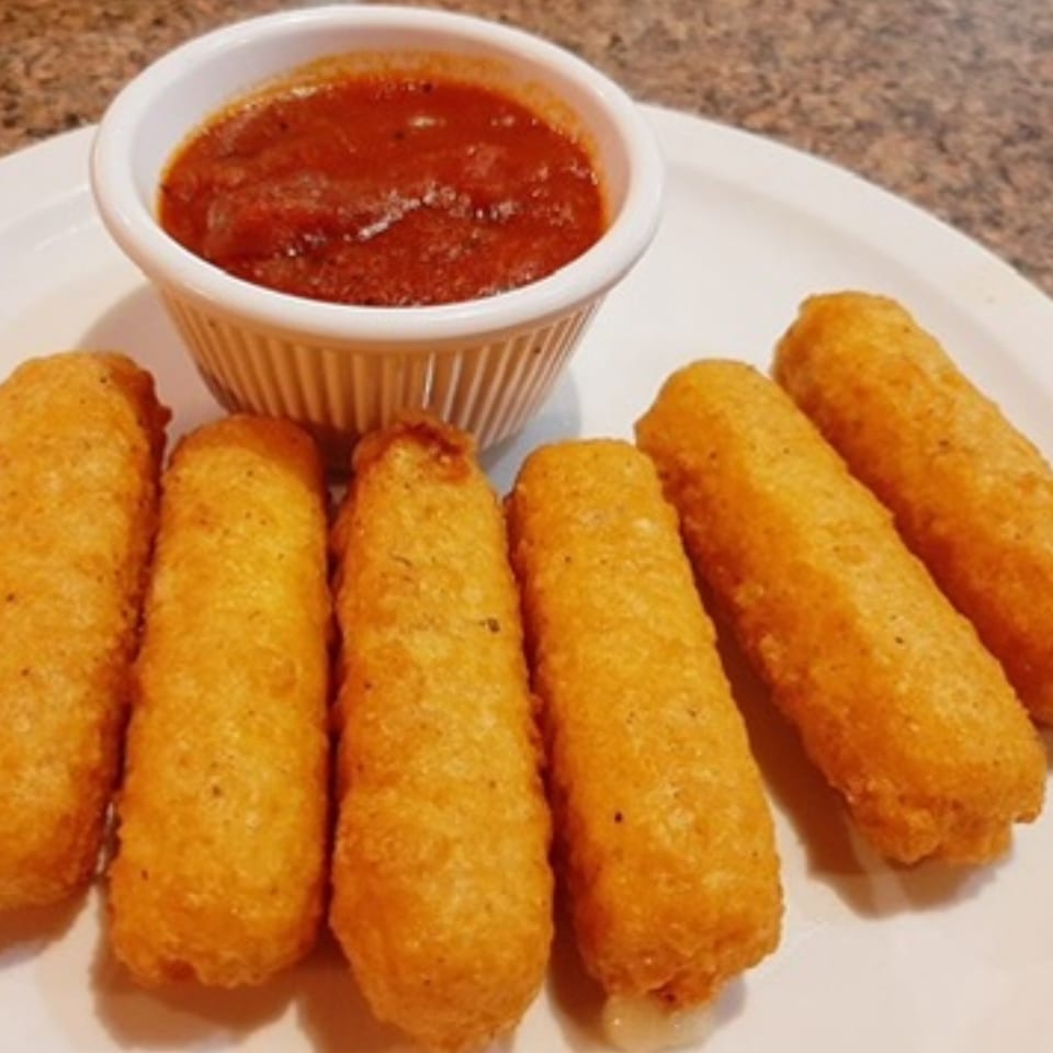 Six golden-brown mozzarella sticks are arranged on a white plate with a side of marinara sauce.