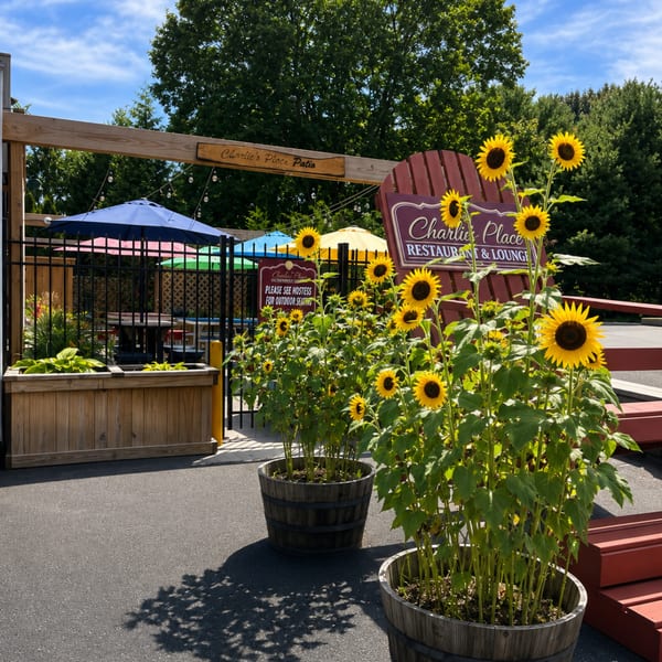 Charlie's Place outdoor patio entrance with sunflowers, colorful umbrellas, and the restaurant sign.