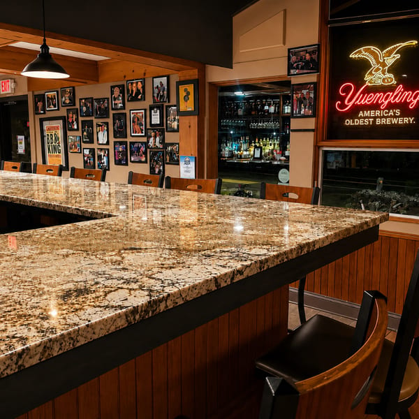 Charlie's Place bar at night with granite counter, framed photos, and a Yuengling neon sign.